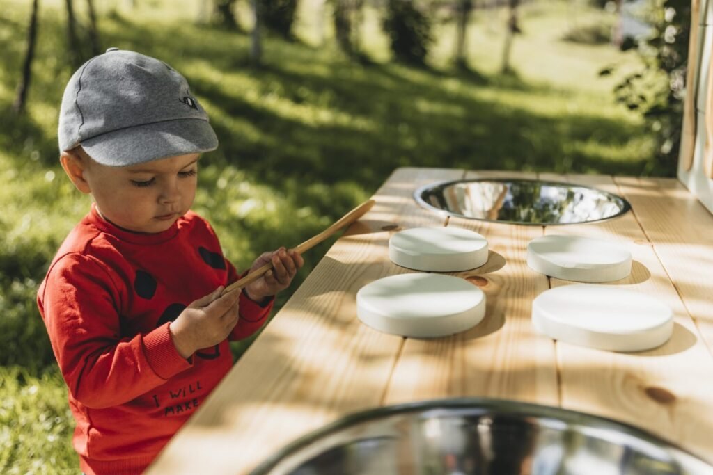 Small children playing together at a wooden mud kitchen