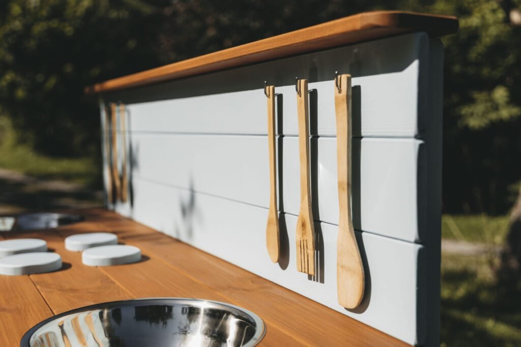 A wooden mud kitchen set up for play in a garden