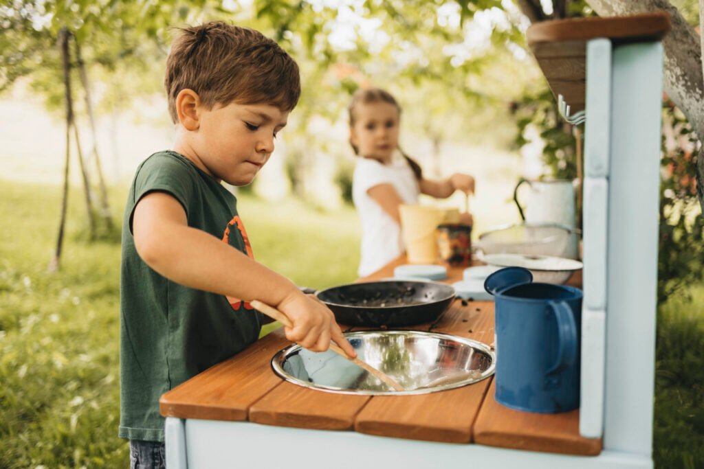 Children cooking together at a wooden mud kitchen
